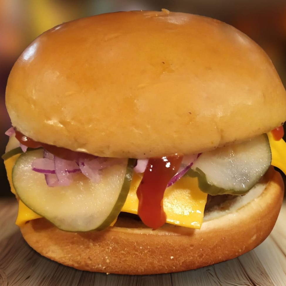 Pão brioche, blend bovino de 150g Artesanal, queijo cheddar, cebola roxa, picles e ketchup.