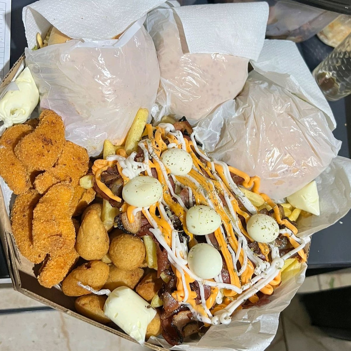 3 x-tudos, batata c/cheddar, Catupiry, bacon, calabresa, orégano, ovo de codorna, salgadinhos e nugguets