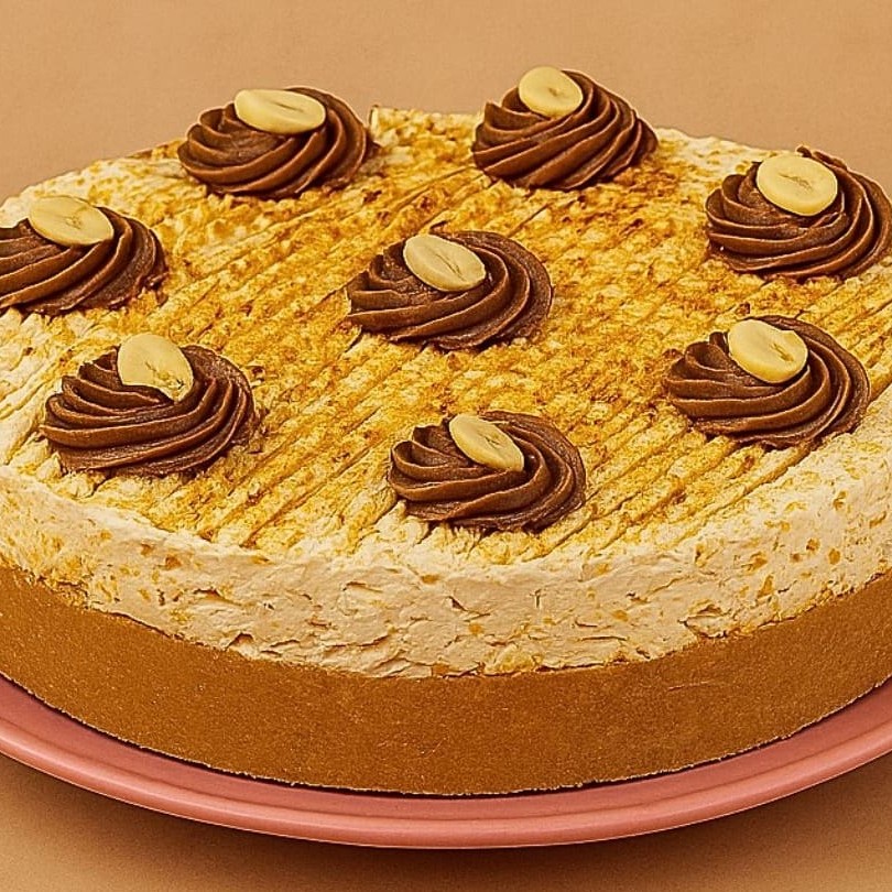 Apresentamos a Mini Skypeanut, uma sofisticada mini torta de 15cm. Esta delícia é elaborada com uma base crocante de biscoito, recheada com nosso exclusivo caramelo salgado, que proporciona um equilíbrio perfeito entre o doce e o salgado. Além disso, contém um irresistível brigadeiro gourmet de paçoca, que é um verdadeiro festival de sabores para o seu paladar. Para completar, temos uma super finalização com um leve e aveludado chantilly de doce de leite. Esta mini torta é a combinação perfeita de texturas e sabores, tornando-a uma verdadeira tentação!