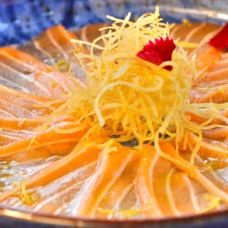 Usuzukuri de salmão é lâminas finas de peixe cru , com cebolinha, gergelim, raspa de limão , azeite trufado, flor de sal,siciliano,crispy de alho poró acompanhado com molho ponzo