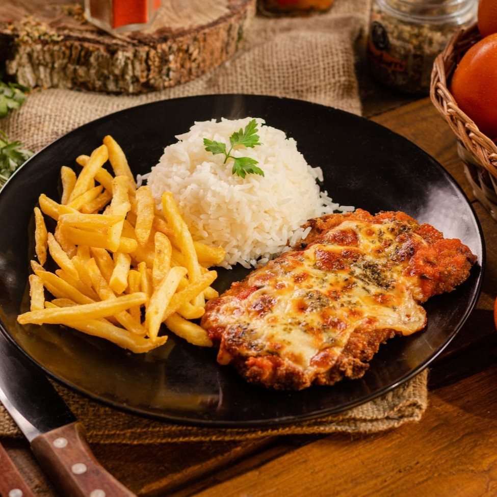 Desfrute da perfeita harmonia entre a suculência do frango e a textura crocante nesta releitura única. Peitos de frango tenros são habilmente empanados em uma mistura de panko e queijo parmesão, criando uma crosta dourada e irresistível. Cobertos com nosso molho de tomate artesanal e queijo derretido, cada garfada é uma explosão de sabores que eleva o clássico parmegiana a novas alturas. Uma experiência gastronômica que satisfaz os sentidos e deixa um sabor memorável.