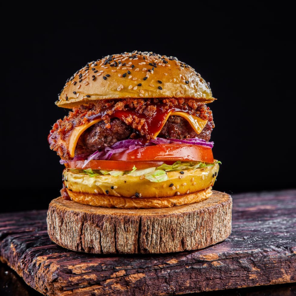 Vem de barbecue e bacon! Pão brioche gergelim, blend bovino 120g, fatias de queijo cheddar, molho barbecue, farofa de bacon , tomate ,cebola roxa e folhas frescas de alface.