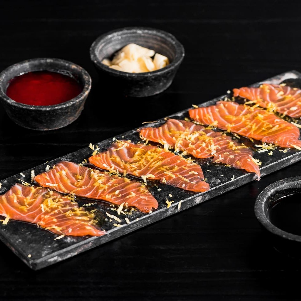 Lâminas de salmão finalizado com azeite trufado e raspas de limão.