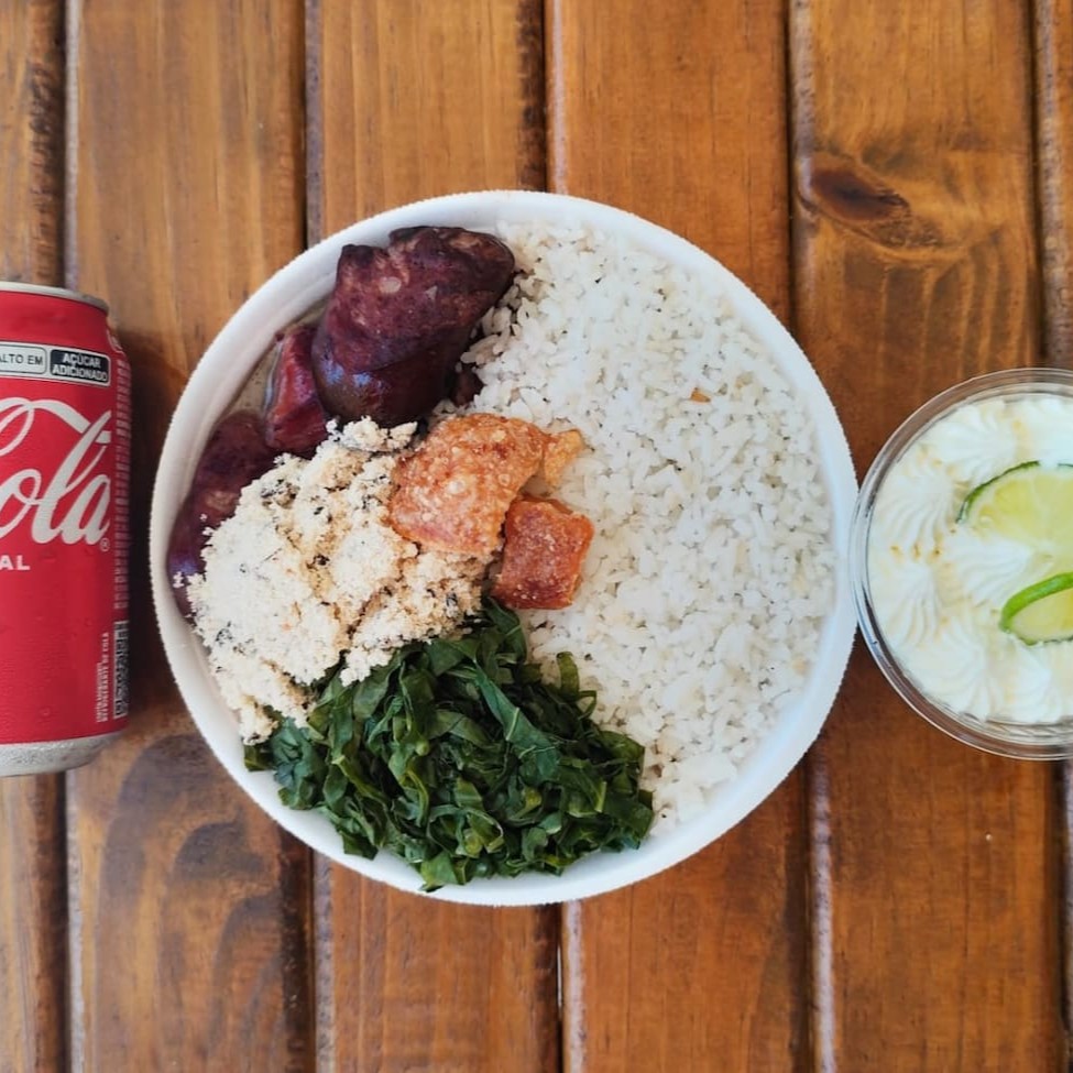 Uma deliciosa mini quentinha de feijoada acompanhada de arroz branco, couve refogada, farofa da casa e torresmo crocante, mais uma sobremesa  e uma lata de coca cola de 350ml. Almoço perfeito sugerido para 01 pessoa com 500gramas. Almoço completa com bebida e sobremesa.
