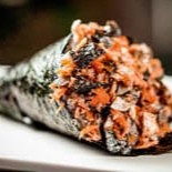 Cone enrolado de alga, com recheio de pele de salmão grelhado, arroz, cebolinha e gergelim.