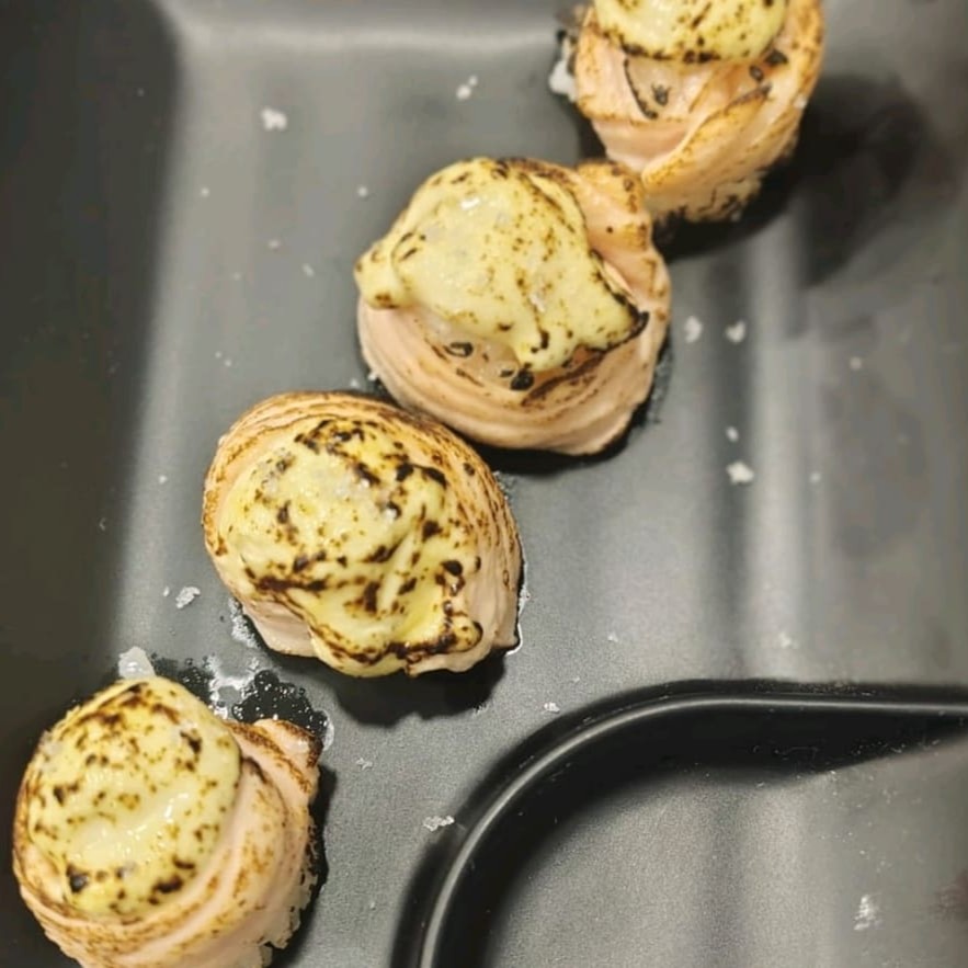 Neta de salmão enrolado em volta de arroz, recheado com pasta de gema de ovo e azeite trufado, massaricado .