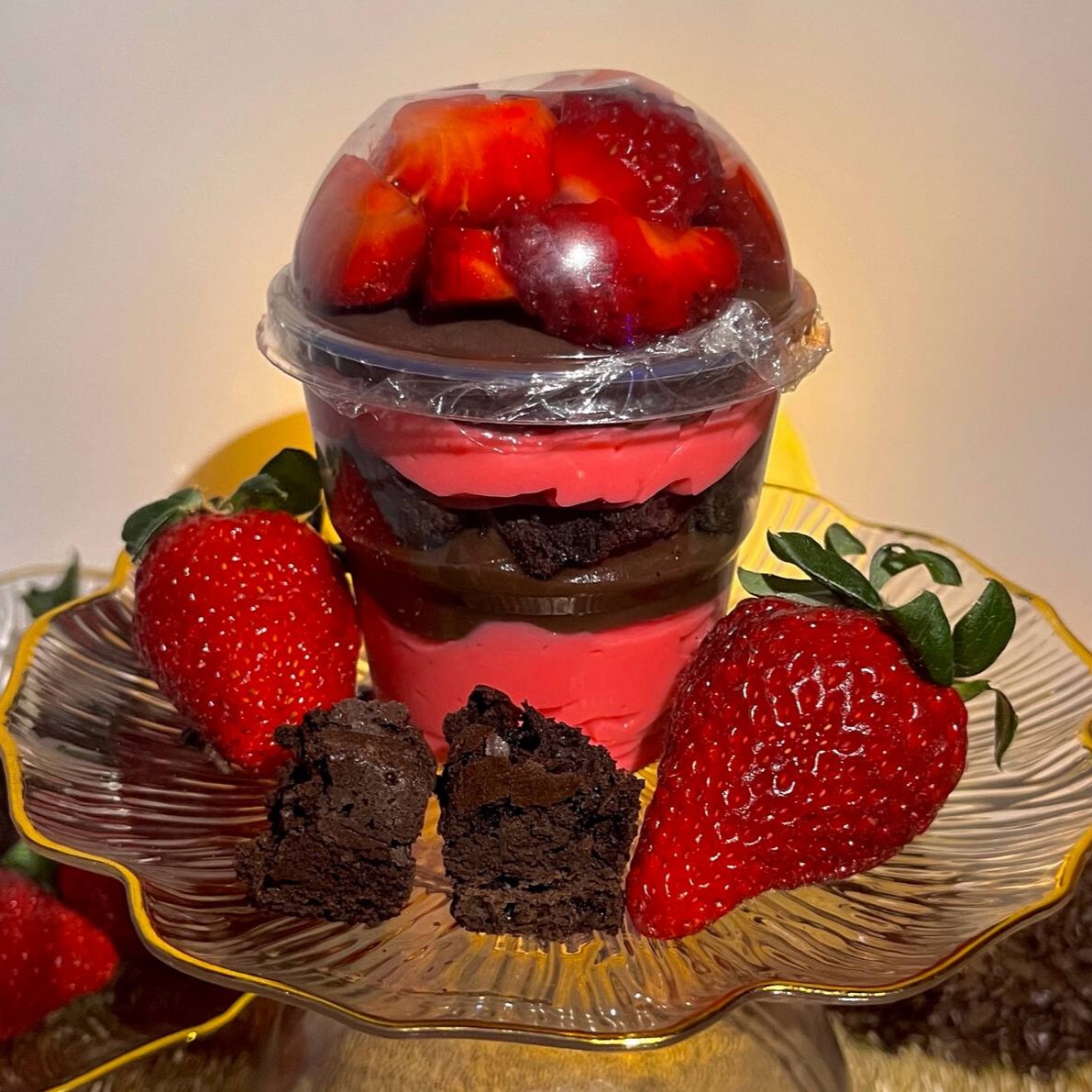 Camadas de brigadeiro 50% cacau, mousse de maracujá, brownies e morangos cortados em cima.