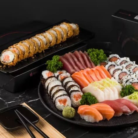 Delicioso combo com 6 sashimis de salmão, 6 sashimis de atum, 6 sashimis de peixe branco, 12 filadélfias salmão, 12 uramakis salmão, 2 sushis salmão, 2 sushis atum, 2 sushis peixe branco e 12 hots filadélfia salmão.