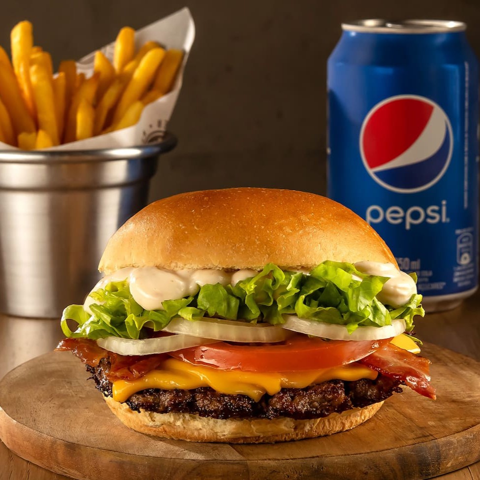 Delicioso Burger de carne black angus de 80g prensado na chapa, coberto com queijo prato, bacon crocante, tomate, alface, cebola e molho da casa à base de alho no pão brioche + batata palito P + bebida.