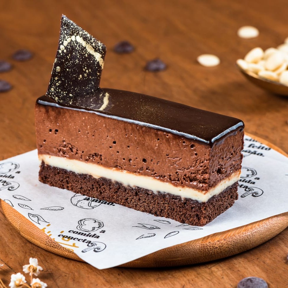 Biscuit Genoise, mousse de chocolate meio amargo belga com ganache de chocolate branco belga.  Finalizado com glaçagem de cacau.