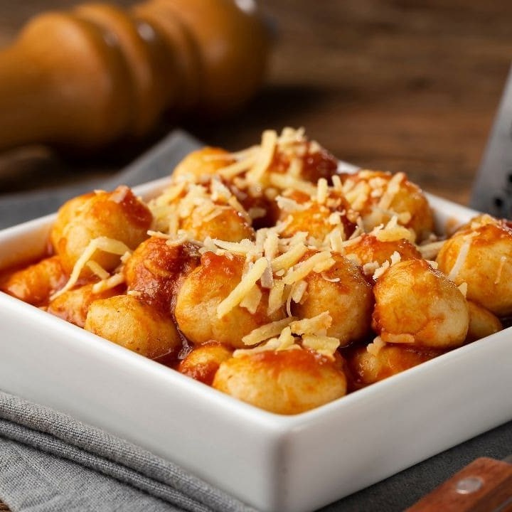 Por cima mussarela levemente gratinada, massa de nhoque de batata fresca com delicioso molho a bolonhesa com tomate e cebola picadinho..