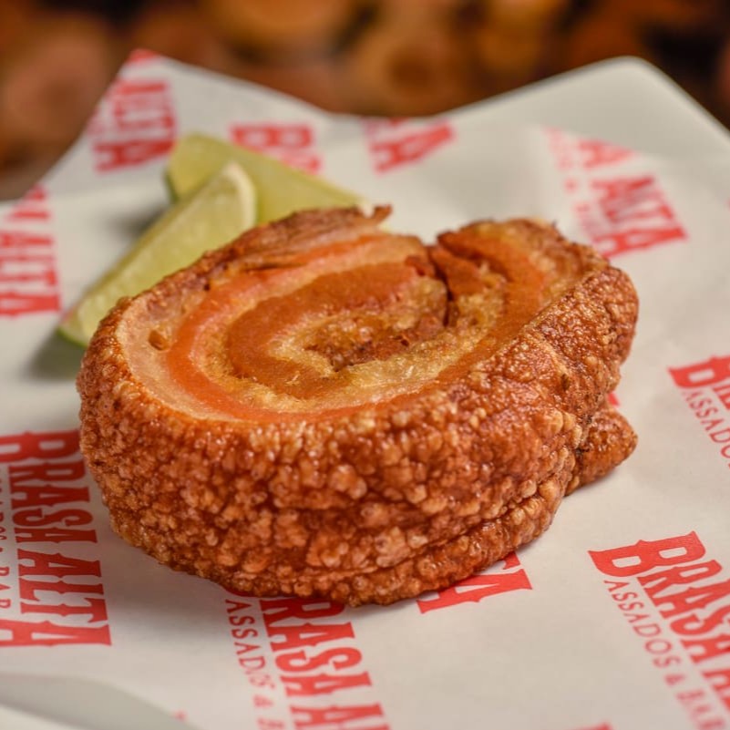 Crocante torresmo de panceta, preparado à moda da casa, acompanha fatias de limão.