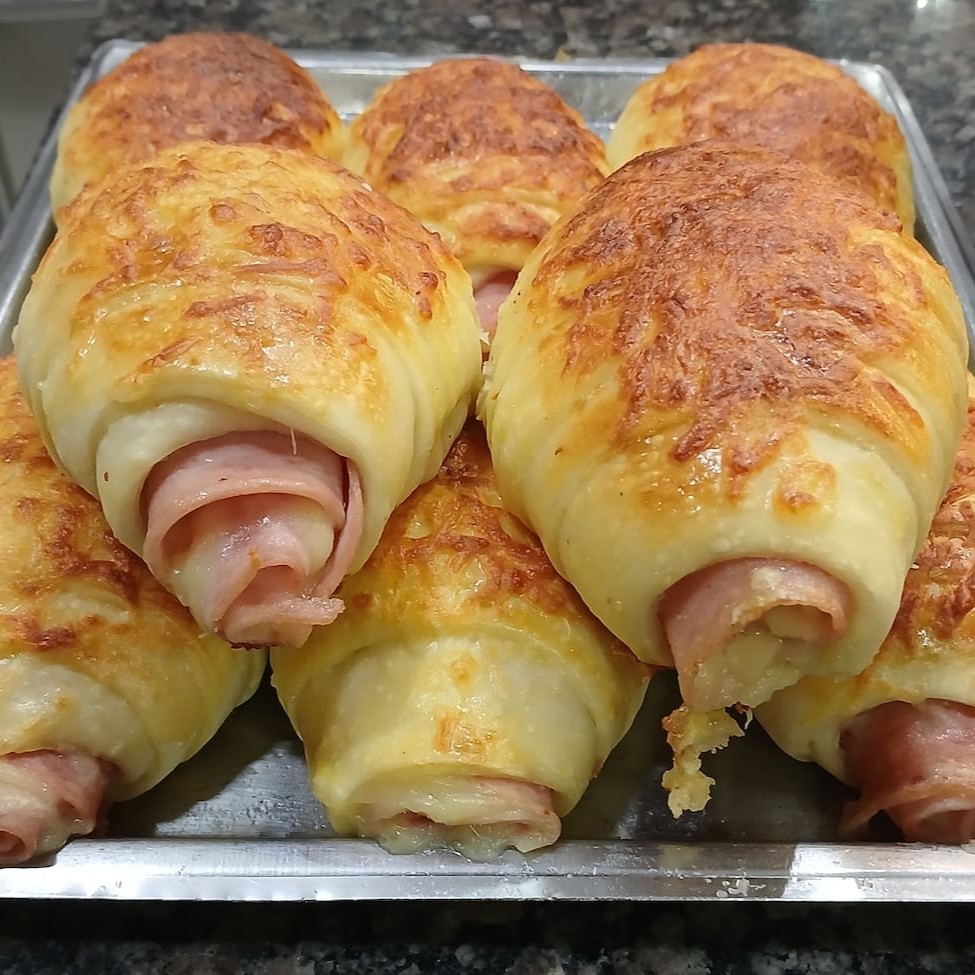Delicioso croissant recheado com queijo, presunto e parmesão, perfeito para um lanche sofisticado e saboroso.