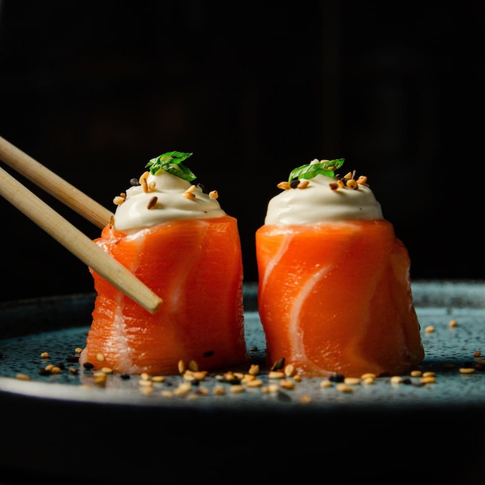Salmão enrolando arroz com cream cheese e um toque de gergelim e cebolinha.