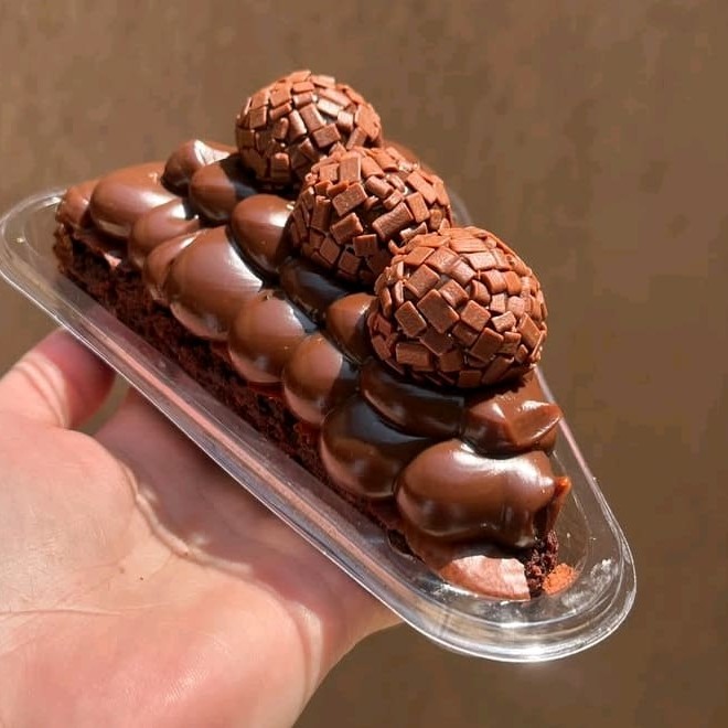 Brownie de chocolate em formato de fatia coberto com brigadeiro cremoso de chocolate.