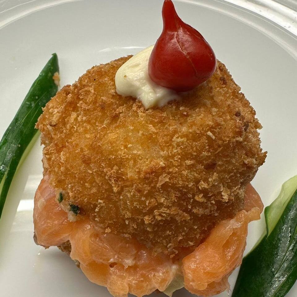 Hamburger feito de arroz, cream cheese, salmão e cebolinha empanado e frito recheado com salmão.