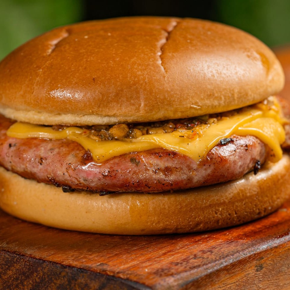 Linguiça artesanal bovina Black Angus com 200g, coberto com 02 duas fatias de queijo prato e geleia de abacaxi com pimenta biquinho no pão brioche super macio. Acompanha batata p + bebida.