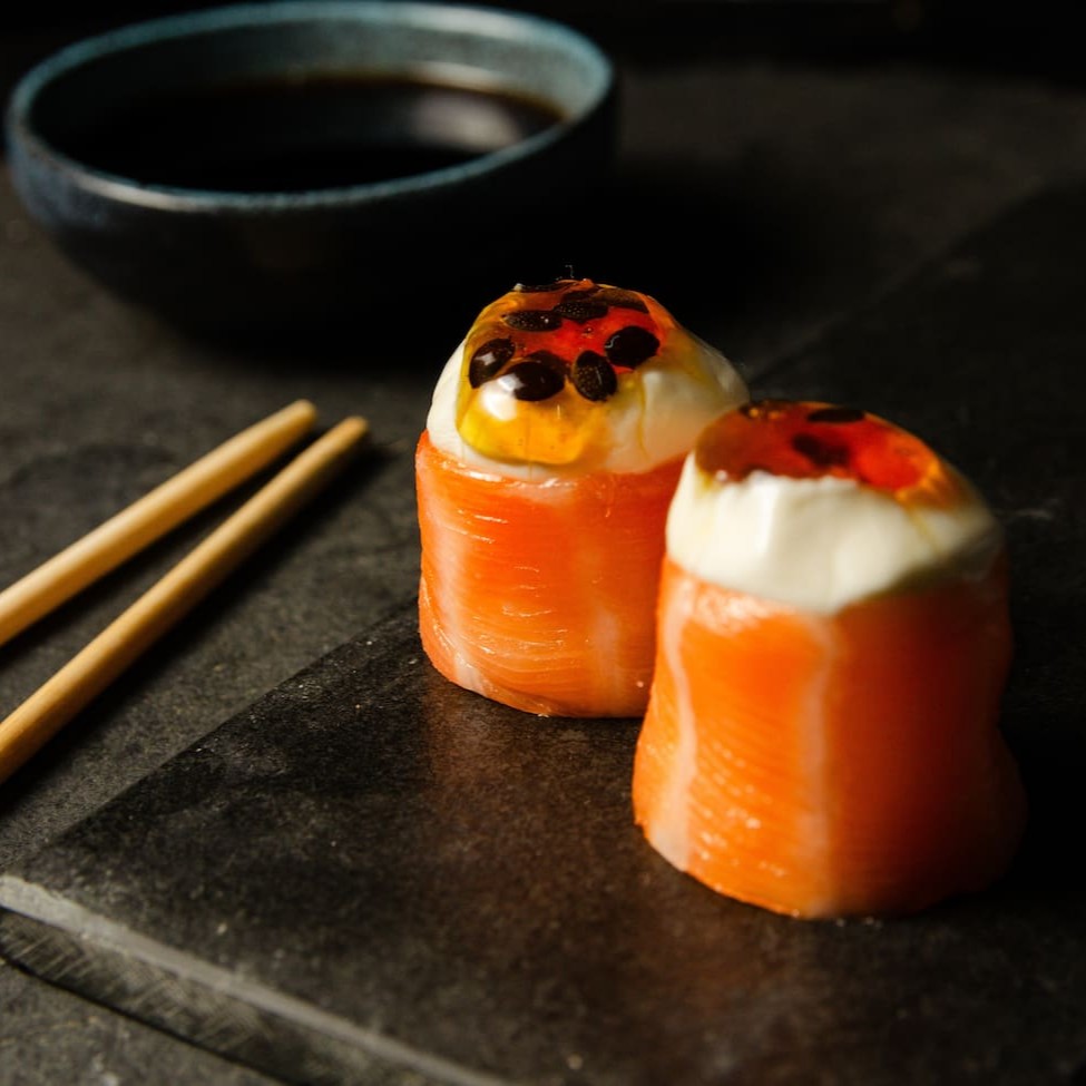 Salmão enrolando arroz com cream cheese e um toque de geleia de maracujá.