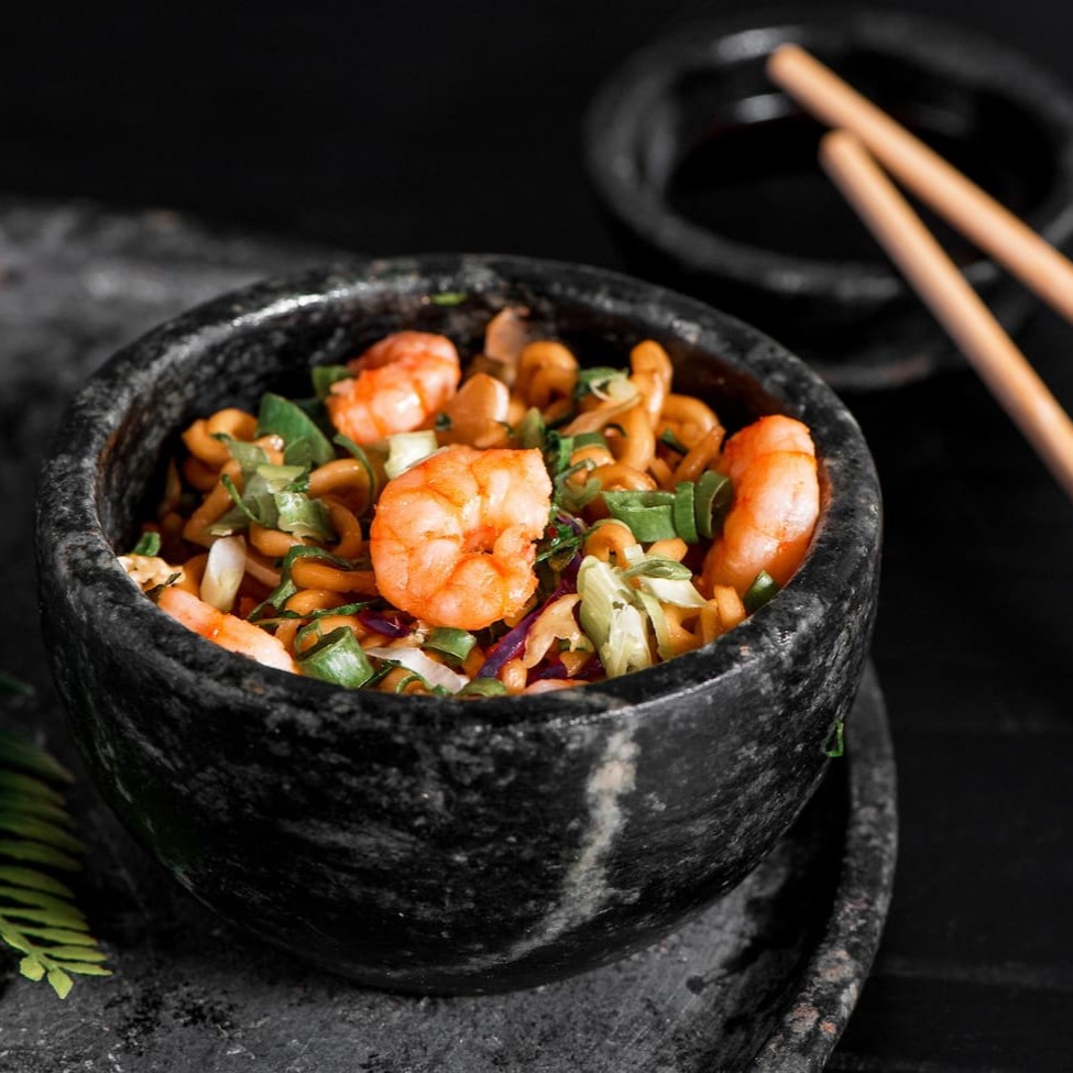 Macarrão oriental refogado com camarão, salmão, lula, cenoura, acelga, couve, repolho roxo e repolho verde, finalizado com shoyu, óleo de gergelim e cebolinha
