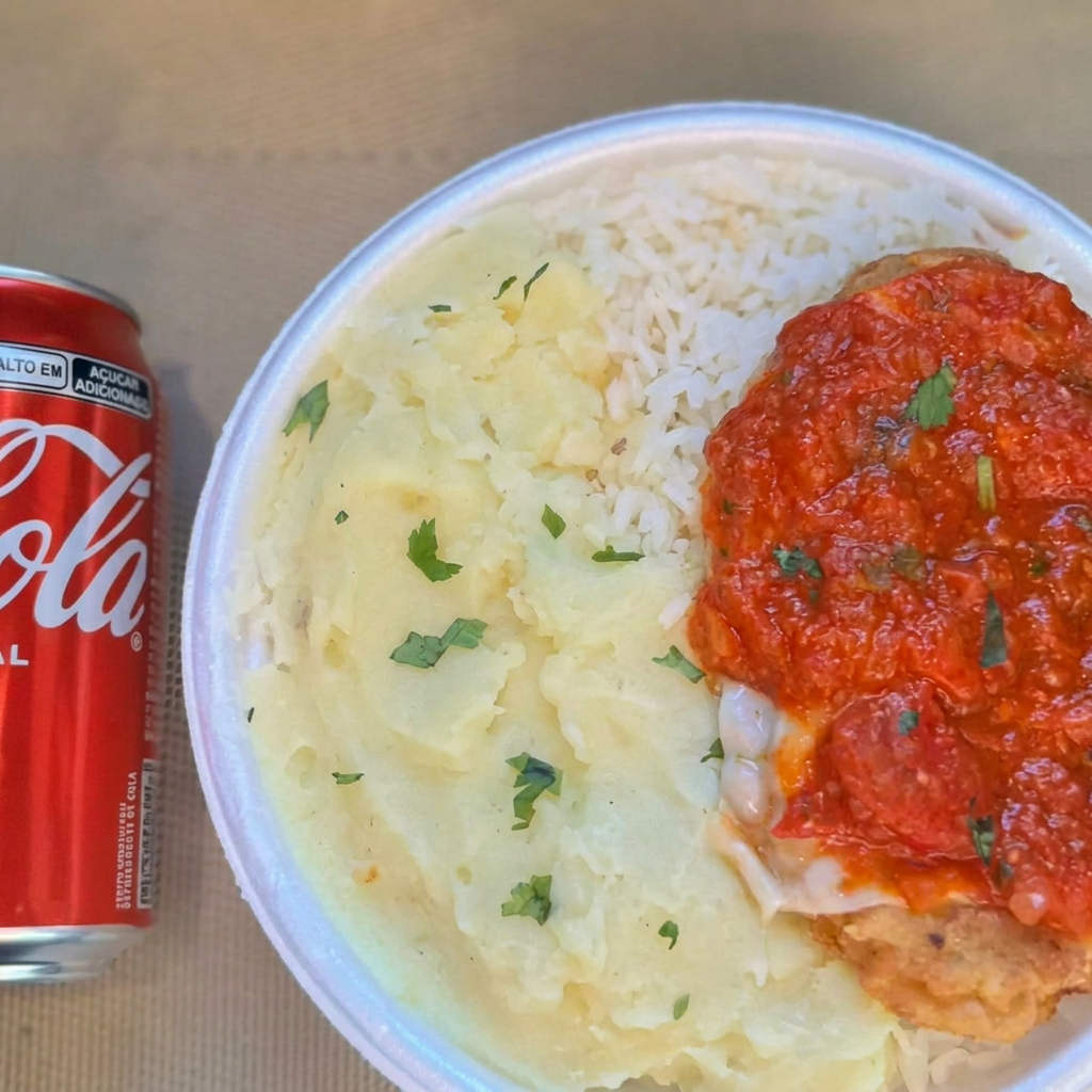 Marmita com delicioso filé de frango parmegiana (empanado na massa crocante coberto com molho de tomates e queijo) acompanhado de arroz branco, feijão e purê batata. Acompanha refrigerante lata Coca Cola 350ml, marmita indicada para 01 pessoa.