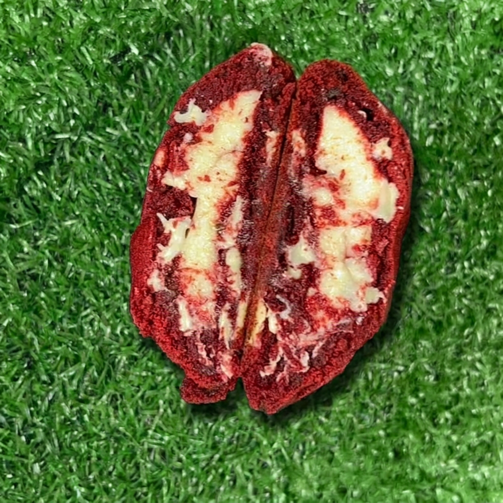 Descubra o nosso exuberante Cookie 'Red Velvet'. Esta criação é feita com uma massa divinamente aveludada de Red Velvet, recheada com um luxuoso brigadeiro de quatro leites. O toque final fica por conta do irresistivelmente cremoso cream cheese e uma geleia de frutas vermelhas, que adiciona um sabor adocicado e levemente ácido. Uma combinação perfeita de texturas e sabores que vai encantar seu paladar!