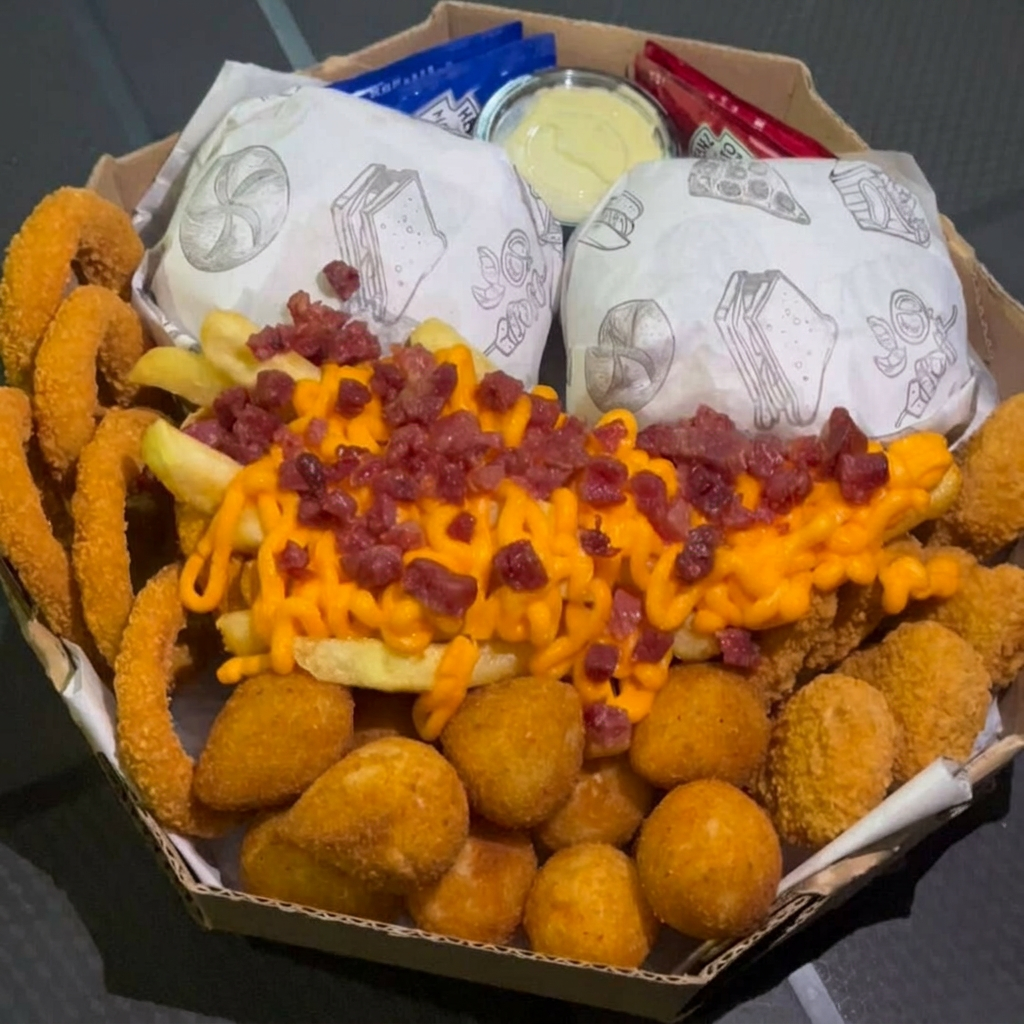 2 Hambúrgueres + Porção de Batata Cheddar Bacon + 4un Coxinhas crocantes + 4un Bolinhas de Queijo + 6un Cebola Empanada + 6 Nuggets. Escolha abaixo o seu Burguer favorito