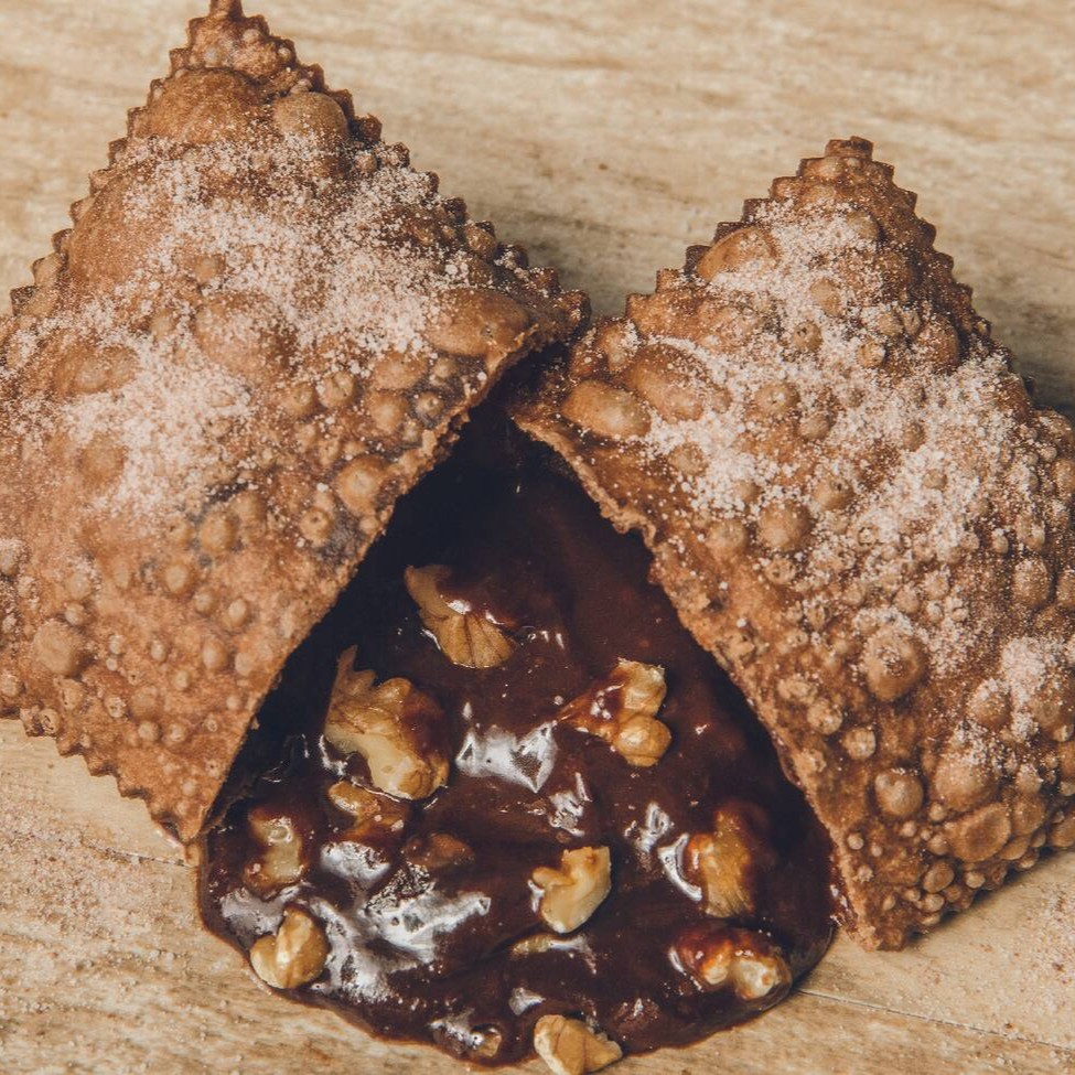 Delicioso pastel polvilhada no açucar e chocolate, recheado com nosso brigadeiro cremoso e nozes crocantes
