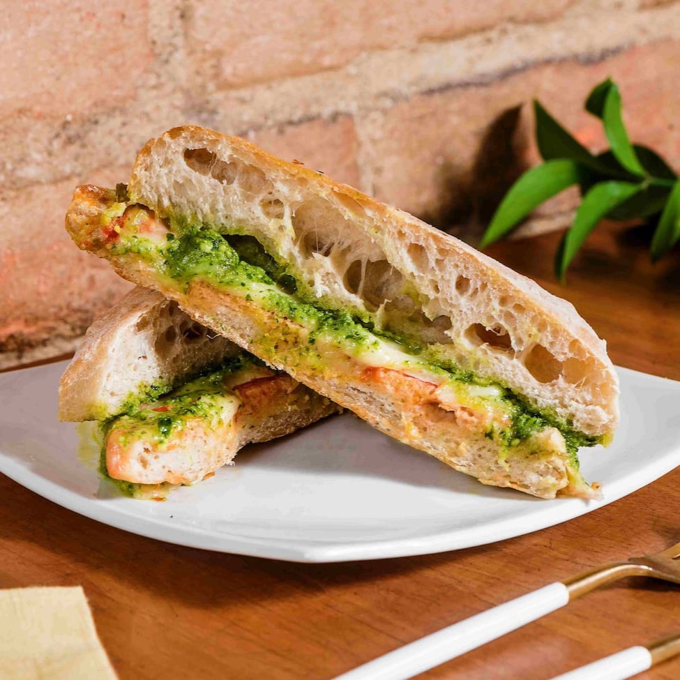 Pão Ciabatta, pomodoro da casa, queijo curado, e pesto de manjericão.