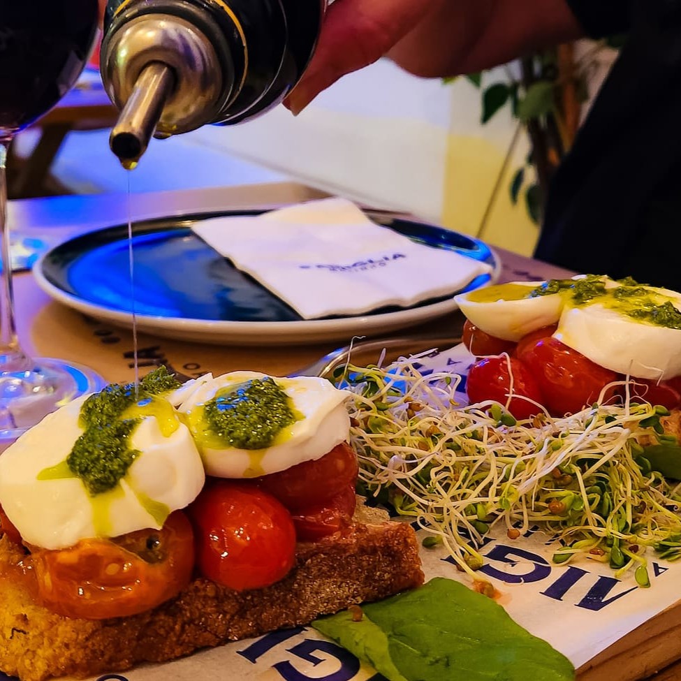 Fatias de pão italiano com tomate cereja  e manjericão.