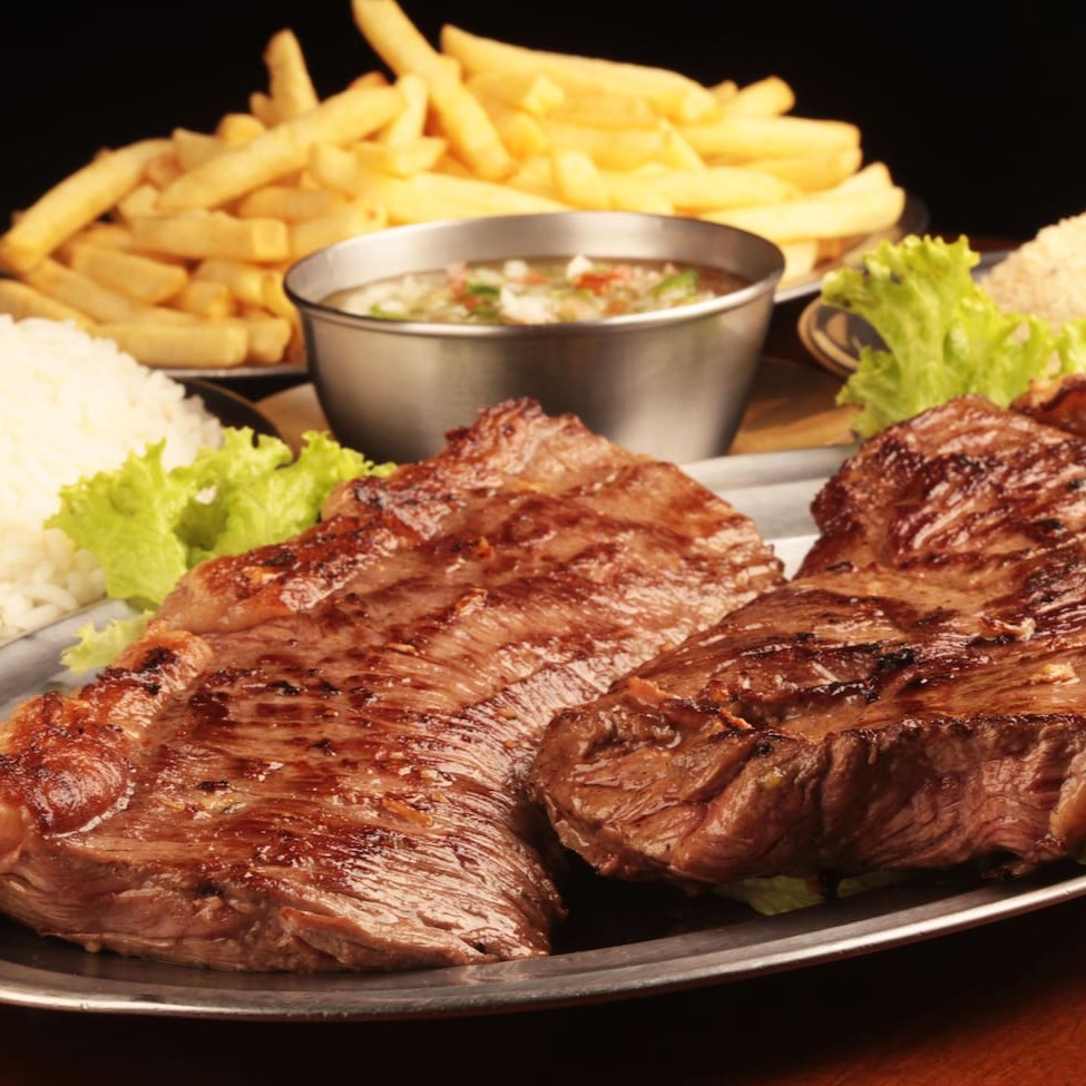 Arroz ,fritas,farofa de ovo , vinagrete e alho sobre a carne