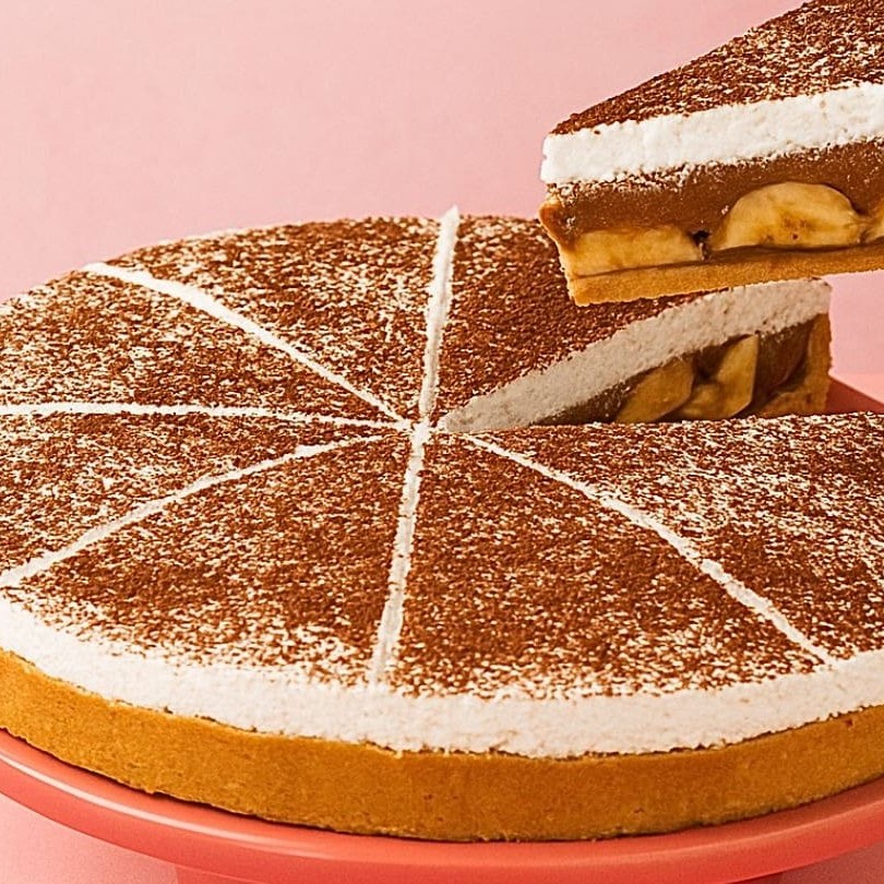 Nossa deliciosa e encantadora Mini Banoffee, com seus generosos 15 cm de diâmetro. Com uma base crocante de biscoito, é generosamente recheada com um sedutor ganache de chocolate, camadas de banana fresca e um irresistível doce de leite. Para finalizar, é coberta com um leve e aerado chantilly, polvilhada com o mais puro cacau em pó. Uma verdadeira delícia para adoçar seu Dia!