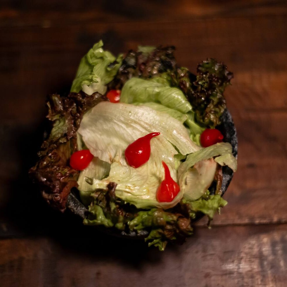 Alface roxa, alface americana, tomate cereja e molho de salada artesanal. A quantidade é indicada para 2 pessoas já levando em consideração outros dois acompanhamentos.