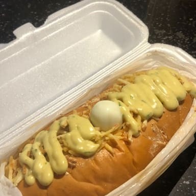 Pão, linguiça, tempero, ketchup, maionese, mostarda, molho Billy Jack, milho, ervilha, ovo de codorna, azeitona, queijo ralado , batata palha e molho verde