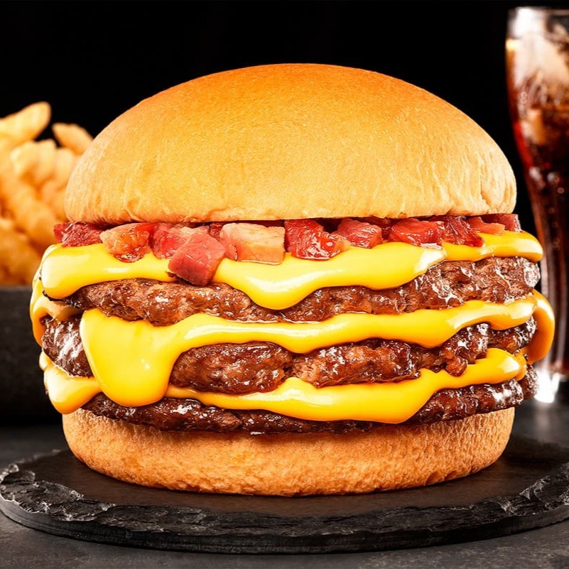 Pão, 3 Blend de 100g ( Smash - Prensado na chapa com aquela crostinha) , Bacon em cubos defumado e o nosso cheddar cremoso artesanal.