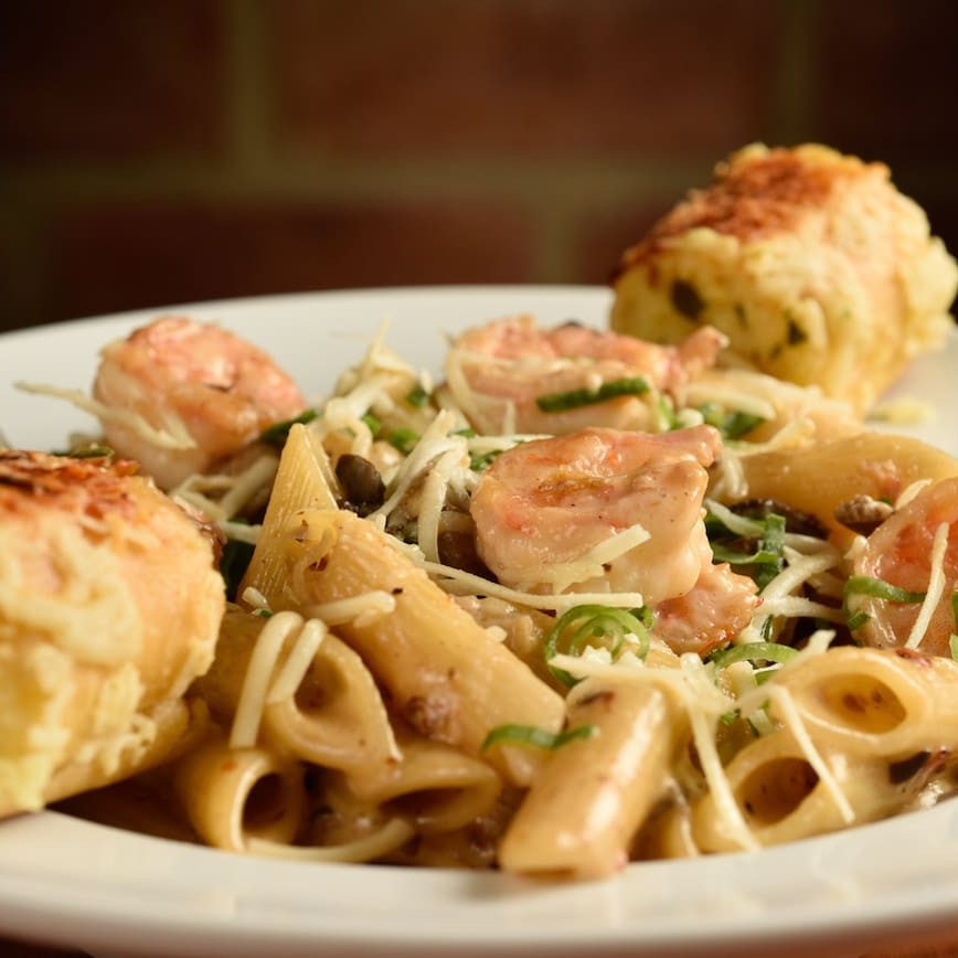 Penne regado ao molho alfredo. Servido com mix de cogumelos selvagens e camarão grelhado. Acompanha pão de alho.