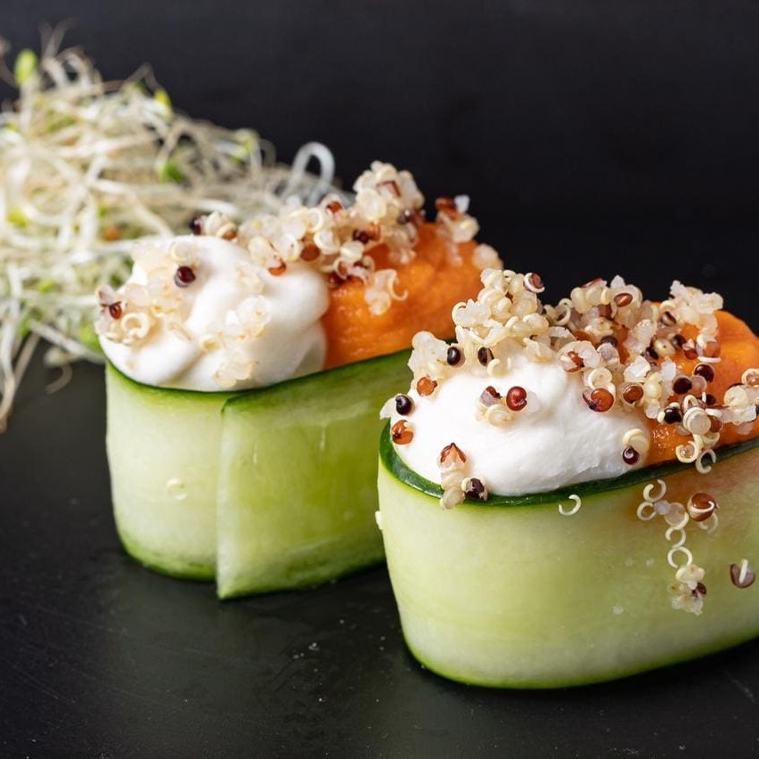 Base de arroz, envolta por pepino, com creme de cenoura, cream cheese (Original ou vegano) e quinoa por cima.