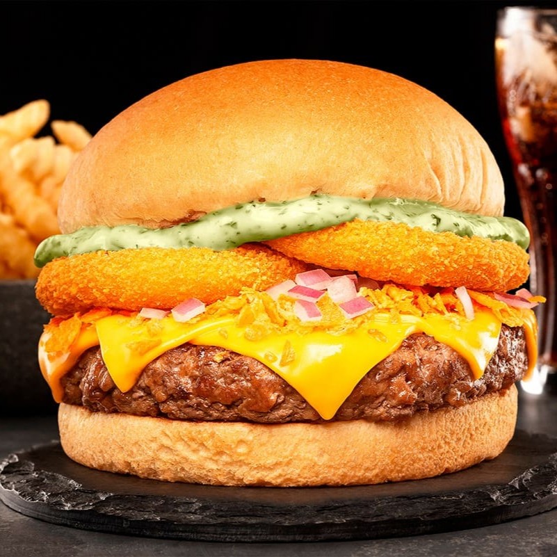 Pão, Blend de 160g, Queijo Cheddar, Maionese de ervas, Cebola roxa picada, Farofa de Doritos e Onion rings.