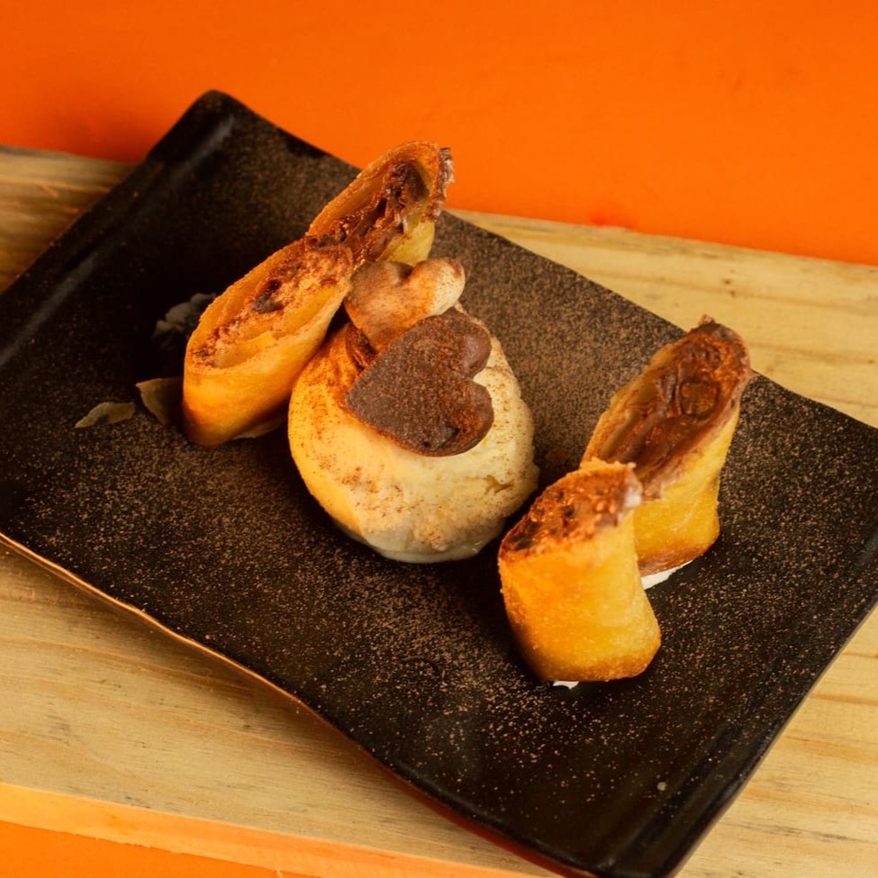 """Porção com 2 unidades de harumaki crocante por fora e recheado com banana macia e docinha, combinada com chocolate derretido e cremoso. Uma sobremesa quente e irresistível, que une a textura sequinha da massa com o sabor marcante e envolvente do recheio."""