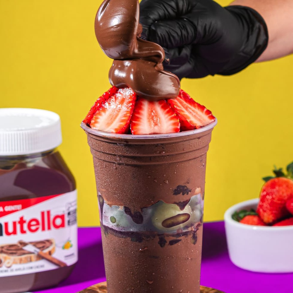 Saboreie nosso autêntico Açaí Tradicional, repleto de pedaços de frutas frescas, generosamente distribuídos no meio do copo e por cima, além disso ainda passamos Nutella no copo e colocamos por cima. Este delicioso manjar é servido em um copo de 300ml, sem economia, garantindo uma experiência gastronômica inigualável. Preparado com uma receita única e inovadora, nosso açaí é cuidadosamente batido com Guaraná, proporcionando um sabor autêntico e surpreendente, que conquista todos os paladares. Além disso, oferecemos uma variedade de complementos gratuitos, para enriquecer ainda mais a sua experiência. Uma combinação saborosa e refrescante, que vai além do convencional. Experimente e surpreenda-se com nosso 'Copo 200ml Nutella', uma inovação na categoria 'Açaí Com Frutas (Pedaços)'!