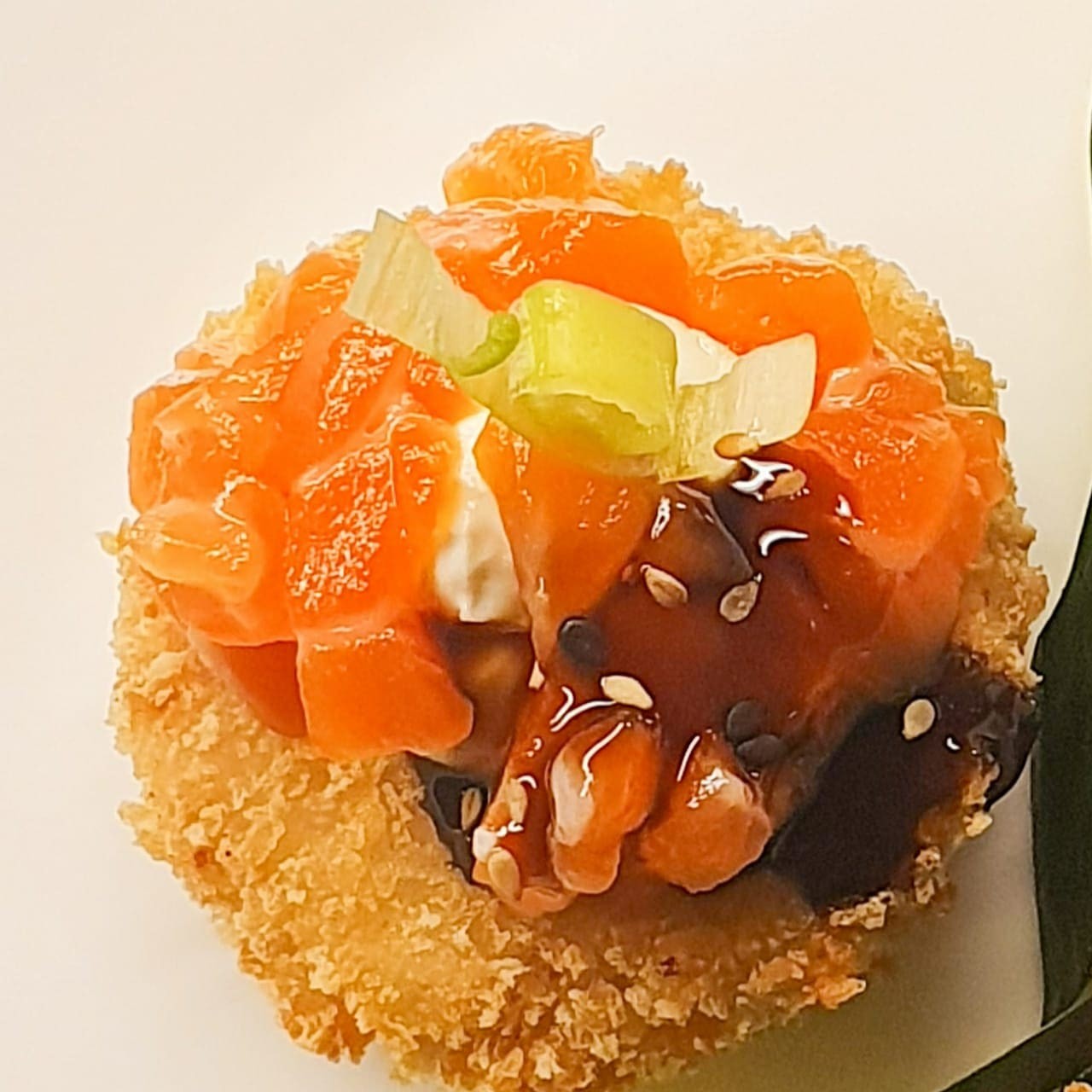 Cookie de arroz, salmão, cebolinha e cream cheese empanado com cobertura de cream cheese e salmão.