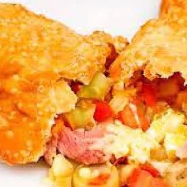 Pastel Portuguesa  Uma verdadeira viagem de sabores! Nosso pastel portuguesa é recheado com uma combinação irresistível de mussarela cremosa, presunto saboroso, ovo cozido em pedaços, pimentão , tomate fresco, cebola crocante, milho , ervilha e o toque final de orégano. Cada mordida é uma explosão de sabores bem temperados, envoltos por uma massa dourada e crocante. É o clássico da pizza, reinventado no formato mais amado do Brasil!  imagem ilustrativa.