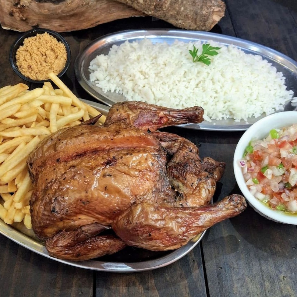 Frango assado e defumado na lenha frutífera, trazendo um sabor único e suculento, com a coloração avermelhada da defumação. Acompanhado de 500g de batata frita ou aipim frito, 500g de arroz, farofa crocante de bacon e molho à campanha. Uma refeição completa para surpreender o paladar!