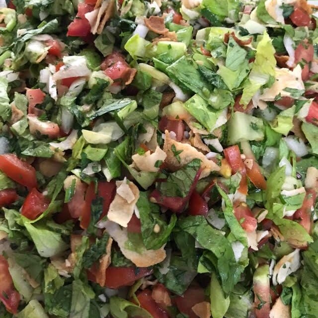 Folhas verdes , tomate , cebola , pao arabe tostado em pedaços.