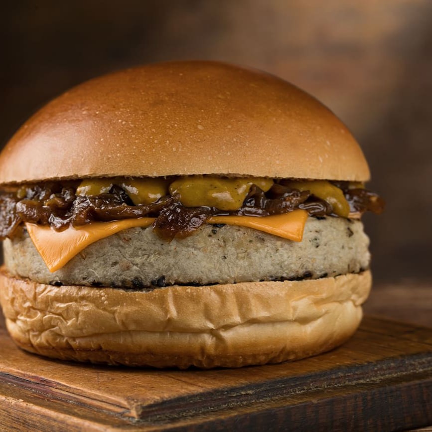 Burger de inhame, quinoa e crocantes de gergelim negro, coberto com queijo prato, nossas famosas cebolas caramelizadas, molho de mostarda levemente adocicada no pão brioche.