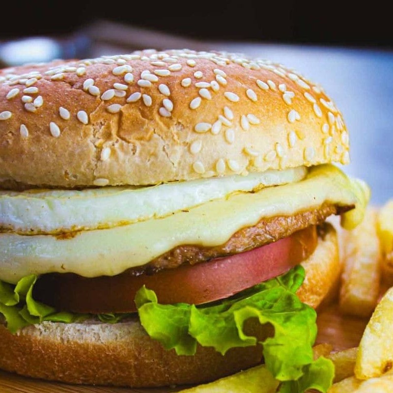 Pão com gergelim, carne, queijo, ovo, alface, tomate e molho