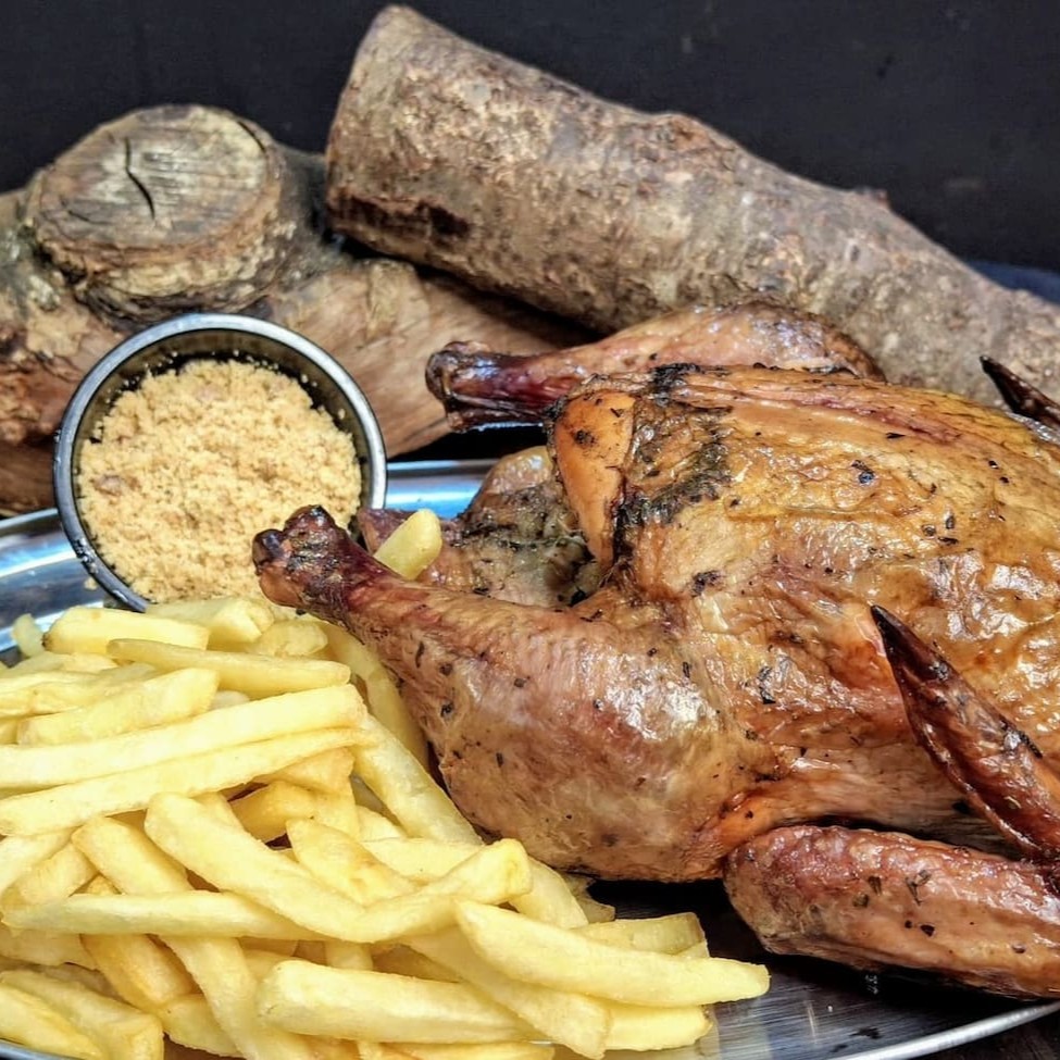 Frango assado e defumado na lenha frutífera, trazendo suculência e sabor único. Acompanhado de 500g de batata frita ou aipim frito e nossa irresistível farofa crocante de bacon. Uma refeição completa e saborosa! Obs: Nosso frango apresenta a coloração avermelhada devido a ação da fumaça (defumação)