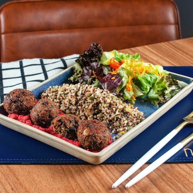 Falafel com pasta hommus de grão de bico pink, mix de grãos e saladinha verde.