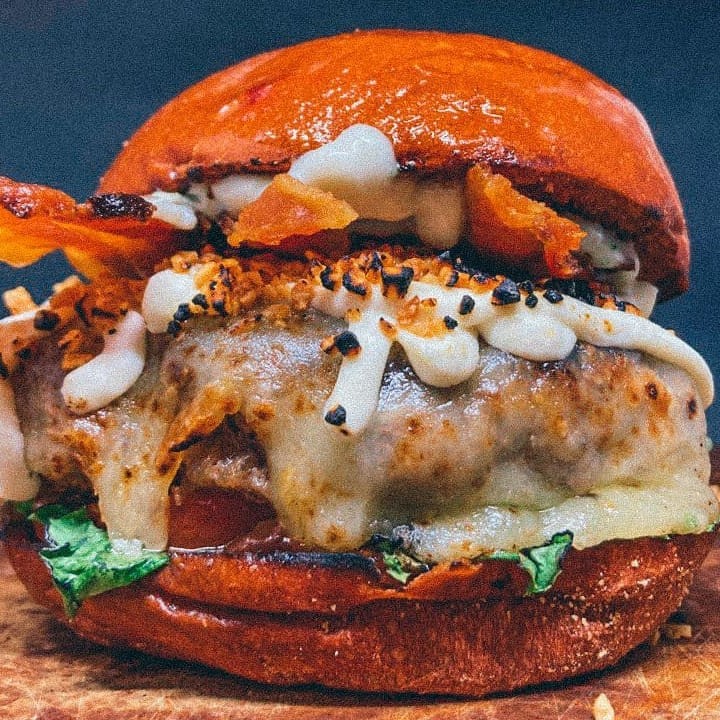 180g de Blend de Angus , queijo derretido , bacon crocante, Cream Cheese, alho frito, Alface, Tomate e Maionese Temperada da Casa no Pão Artesanal selado na Manteiga