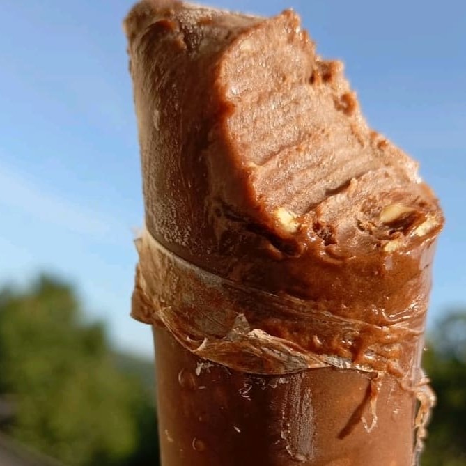 Uma base cremosa de chocolate 50% cacau ao leite e leite condensado, com uma camada de creme de avelã com amendoim