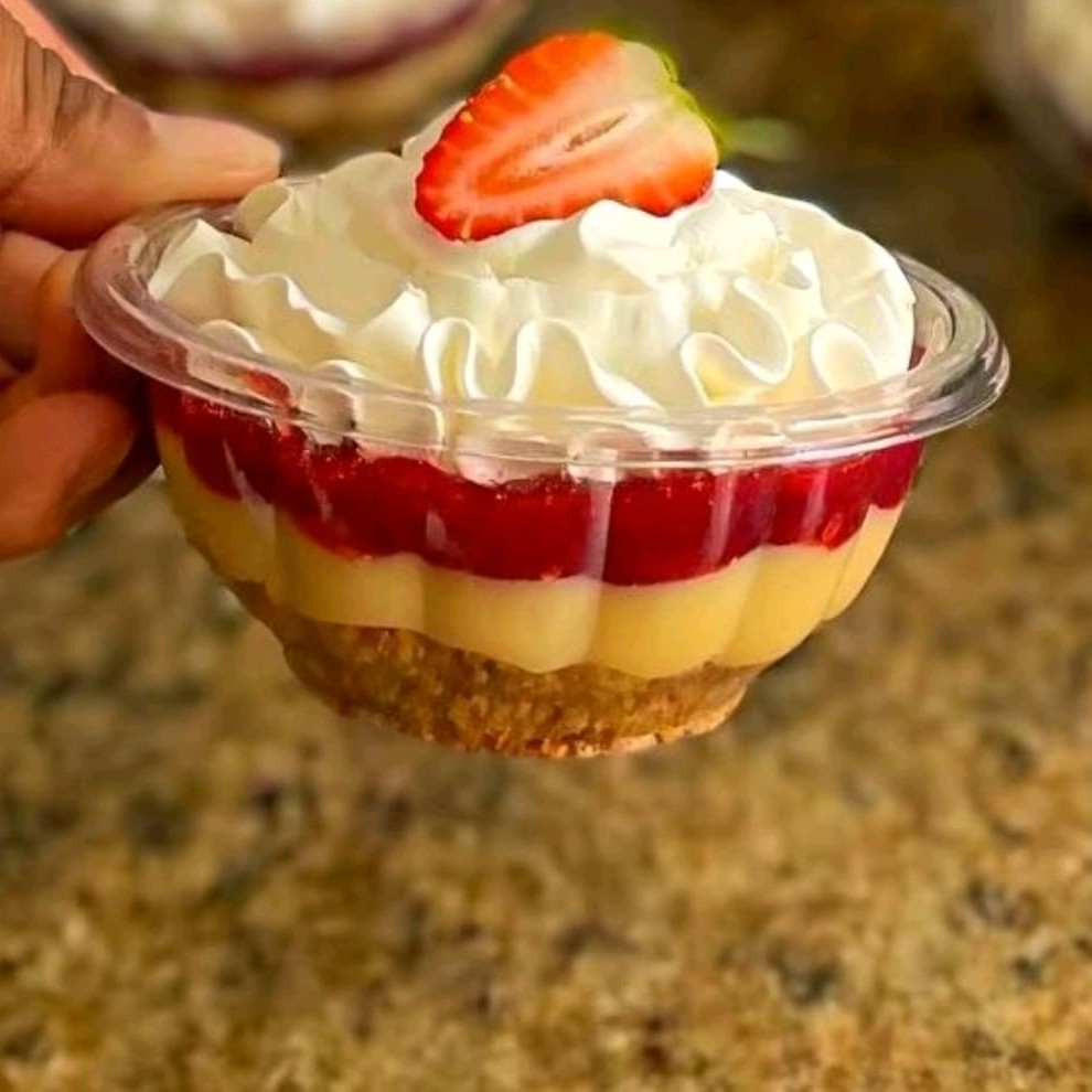 Biscoito triturado com brigadeiro branco , geleia de morango e chantyninho e um pedaço de morango